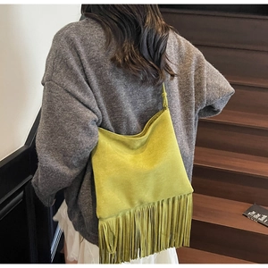 Primer plano detallado del bolso de ante verde mostaza con flecos largos bohemios