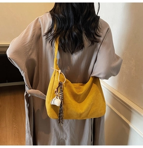 Detail of a bright yellow hobo bag in suede texture featuring a coffee cup fringe charm