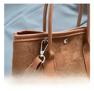Detail of premium silver metal hook and neat stitching on caramel suede bucket bag