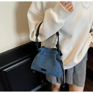 Detail of denim bucket bag with twisted leather handle and adjustable shoulder strap