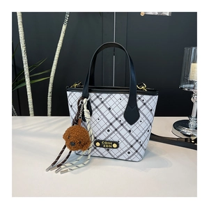 Detail of checkered bucket bag with polka dots, leather handle and cute puppy charm
