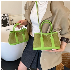 Detail view of two bright green suede bucket bags in medium and mini sizes with silver studs
