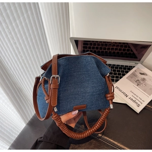 Detail of denim bucket bag showing leather drawstring and spiral textured handle