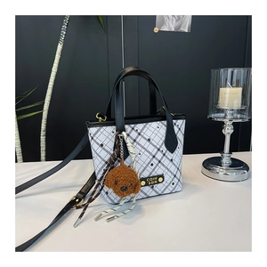Detailed shot of a black and white checkered bucket bag with a cute puppy plush charm
