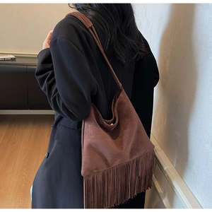 Dettaglio borsa hobo in camoscio marrone con lunghe frange retrò e texture opaca