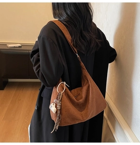 Detail of dark brown suede hobo bag with tassel and coffee cup charm on model