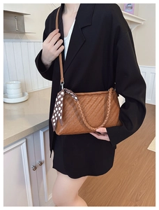 Detail of woven texture on brown shoulder bag with polka dot scarf and leather strap