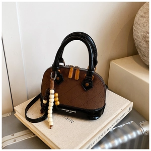 Detail view of quilted brown shell bag with retro beaded charm and dual zippers