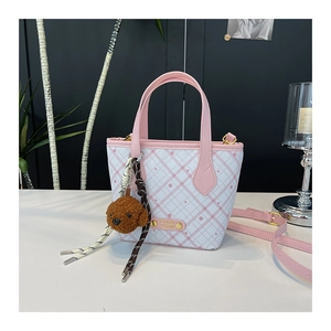 Detailed view of pink plaid tote bag with cute bear plush charm and metal logo plate