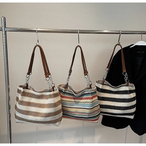 Dettaglio di borse tote intrecciate a righe con cinturini in pelle e catene in metallo