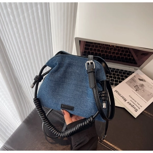 Detail of blue denim bucket bag featuring spiral handle and silver metal adjustment buckle