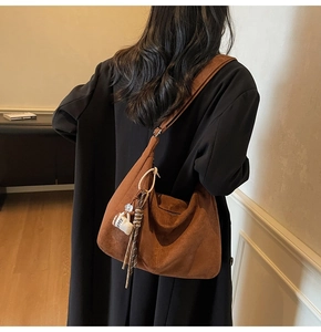 Detail of a large brown suede tote bag featuring a cute coffee cup charm and ribbon