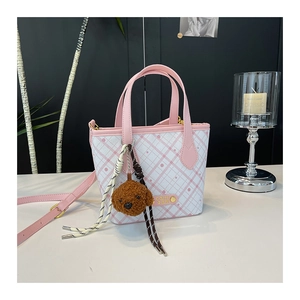 Detail of pink plaid bucket bag with plush bear charm and COIN '20N leather patch