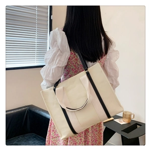 Vue de dos d'un modèle portant un grand sac cabas en toile crème avec des anses noires