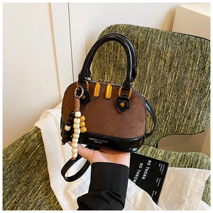 Detail of a brown shell handbag with wood bead charm and diamond stitch pattern