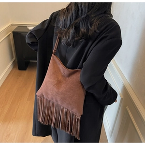 Detalle de bolso hobo de ante marrón con flecos bohemios largos y acabado mate suave