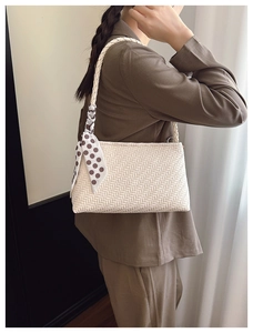 Detailed close-up of cream woven shoulder bag with a silk scarf tied on the handle