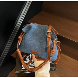Detail showing blue denim bucket bag with brown leather trim and spiral handle