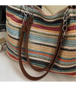 Dettaglio borsa tote in tessuto a righe colorate con manici in pelle marrone e anelli