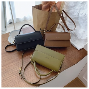 Chic rectangular PU leather bags in black, brown and green on a wooden table