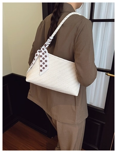 Detail of white woven shoulder bag with chic polka dot scarf accessory on model