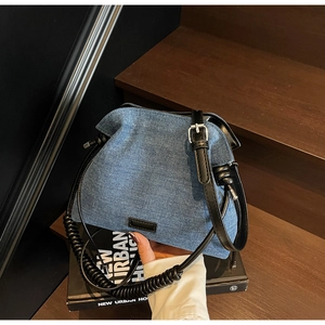 Detail of blue denim shoulder bag with unique black spiral handle on wooden stairs