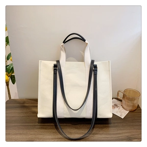Détail d'un sac cabas en toile avec bandoulières noires et surpiqûres blanches