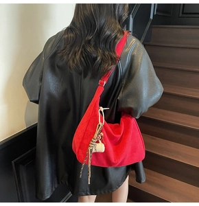 Detail of red suede tote bag featuring a decorative coffee charm and long strap