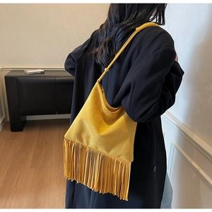 Dettaglio di una borsa a tracolla giallo brillante con frange boho e texture opaca