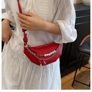 Détail du sac demi-lune rouge à texture tressée, perles et chaîne argentée sur modèle