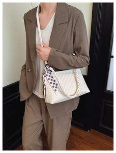 Detailed macro view of woven texture on white shoulder bag with a stylish polka dot scarf