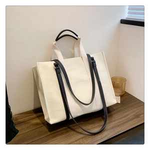Vue détaillée du grand sac cabas en toile avec poignées en cuir noir et bandoulière beige