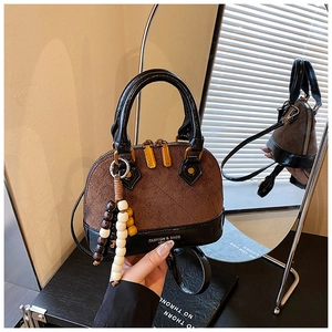 Detail of shell-shaped bag with brown quilted suede, leather trim and beaded charm