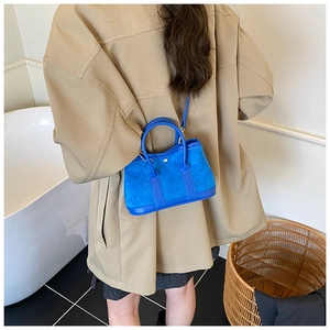 Detail of royal blue suede tote bag with silver circular clasp and slender shoulder strap