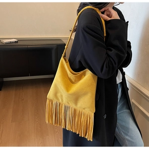 Vista dettagliata della borsa a tracolla in camoscio senape con lunghe frange su un modello