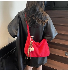 Detail of red suede hobo bag with a coffee cup charm accessory on a wooden staircase