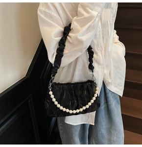 Détail du sac nuage noir à fronces avec chaîne décorative en perles sur le mannequin