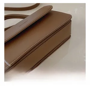 Detailed close-up of brown leather stitching and flap edge of the vintage shoulder bag