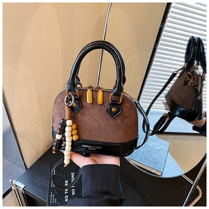 Detail of mini shell bag showing brown suede, black patent leather, and wood bead charm