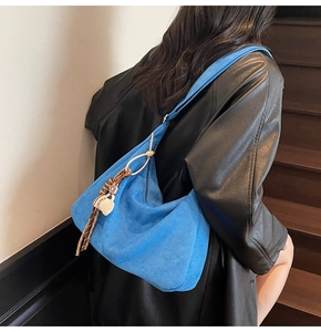 Detail of blue suede hobo bag with COFFEE charm worn with a black leather coat