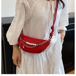 Détail du sac tressé rouge avec breloques en perles et accents de chaîne argentée