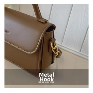 Close-up of golden metal hooks and dark brown leather texture on a vintage handbag