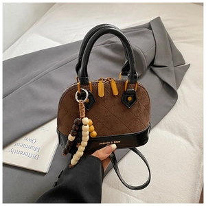 Detailed view of vintage shell bag featuring brown suede stitching and colorful bead tassel