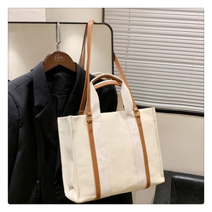 Détail du sac cabas en toile avec tissu crème et poignée en cuir marron contrastant