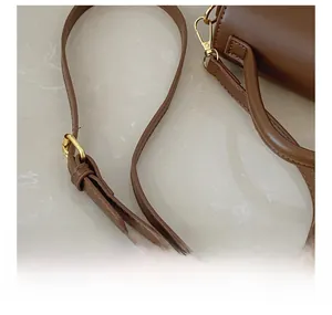 Detail showing adjustable brown leather strap with gold buckle and precise stitching