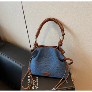 Detail of blue denim hobo bag with spiral brown leather handles and pleated texture