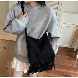 Dettaglio borsa a tracolla in camoscio nero stile bohémien con lunghe frange su modella