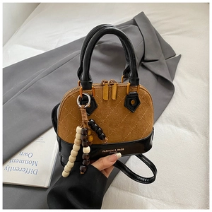 Detail of a vintage-style shell bag featuring brown matte and black quilted leather textures