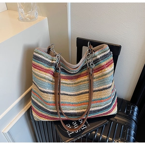 Dettaglio borsa shopper intrecciata a righe con manici in pelle e catene metalliche