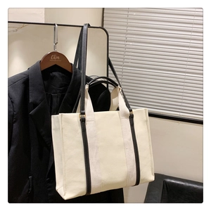 Vue détaillée du sac cabas en toile beige avec poignées et finitions en cuir noir